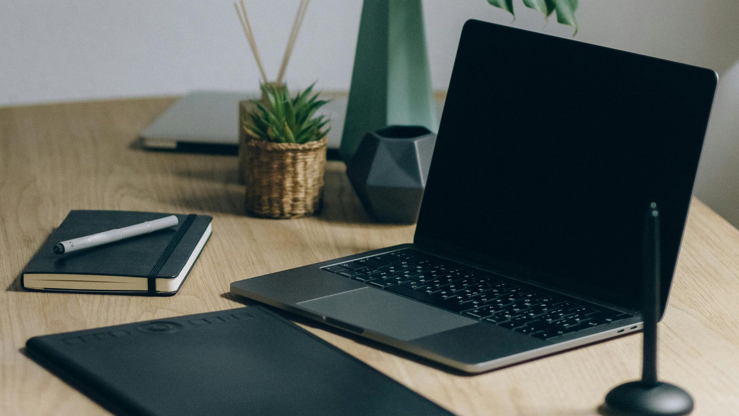 black laptop and black notebook on a desk for small business owners looking to optimize their technology