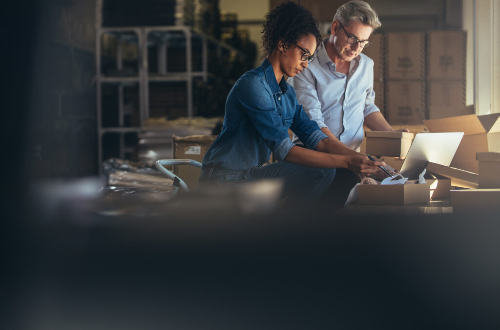 two people work together packaging items and working on a computer in a small business